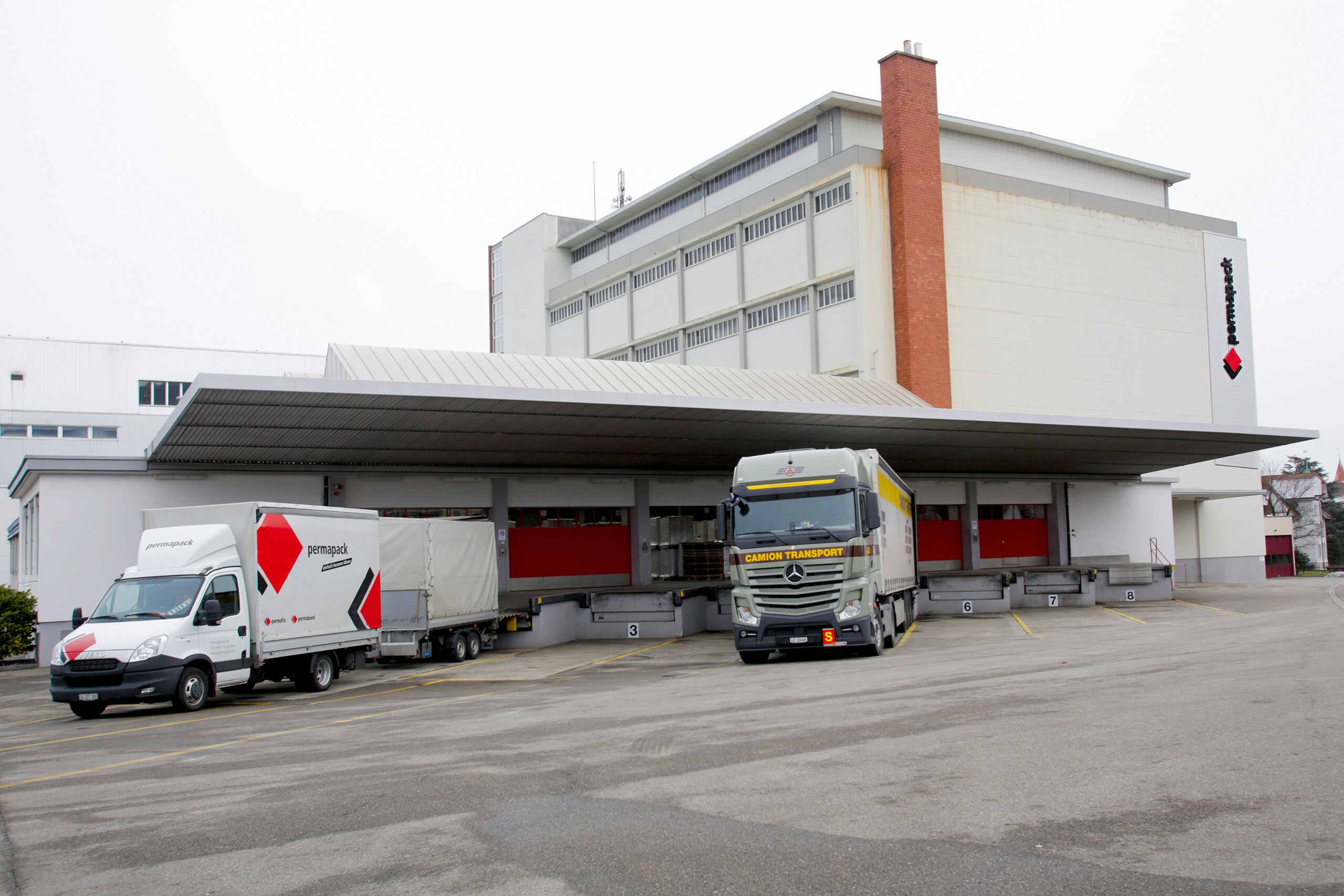 Logistikgebäude mit Lastwagen an Laderampen