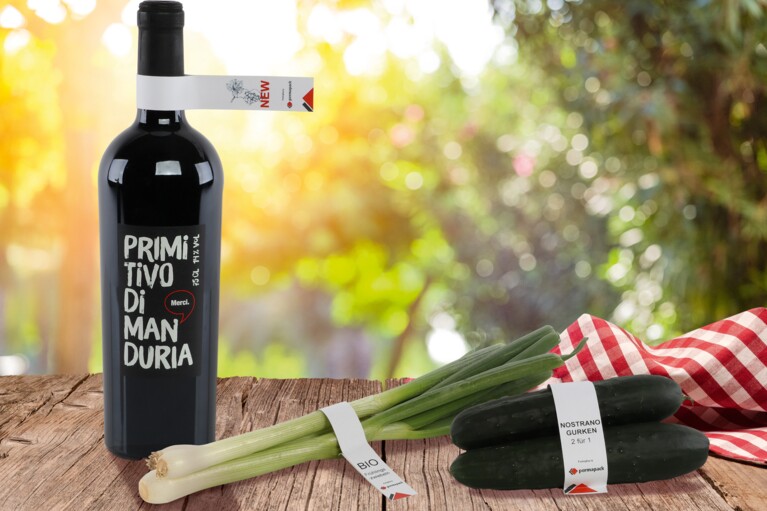 Eine Flasche Wein, Frühlingszwiebeln und Gurken mit LoopTack-Etiketten.