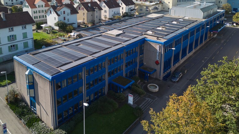 Le bâtiment bleu de Permapack avec une installation photovoltaïque sur le toit.