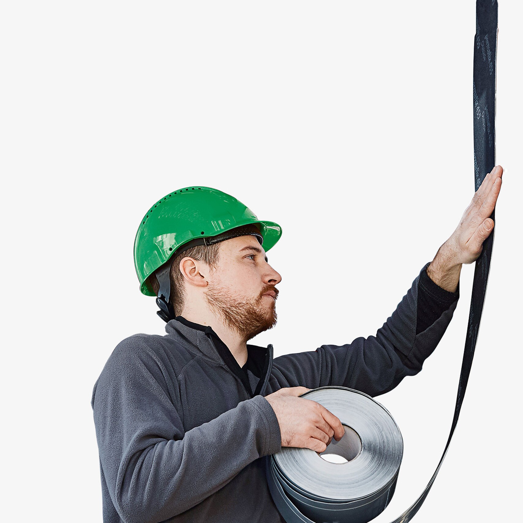 Un ouvrier portant un casque vert applique un ruban d'étanchéité sur un mur