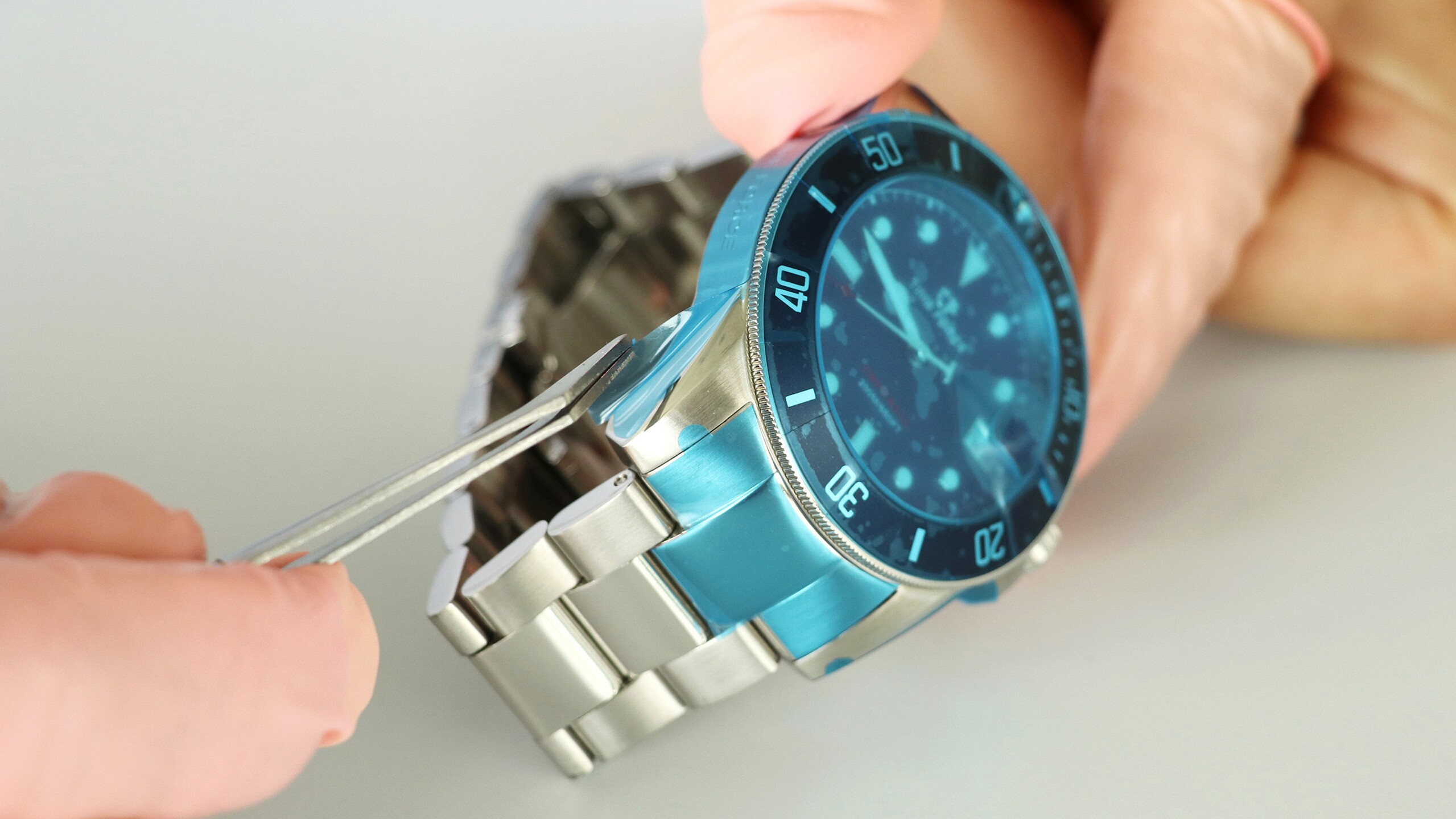 Blautransparente Formstanzteile auf einem Metall-Uhrenarmband.