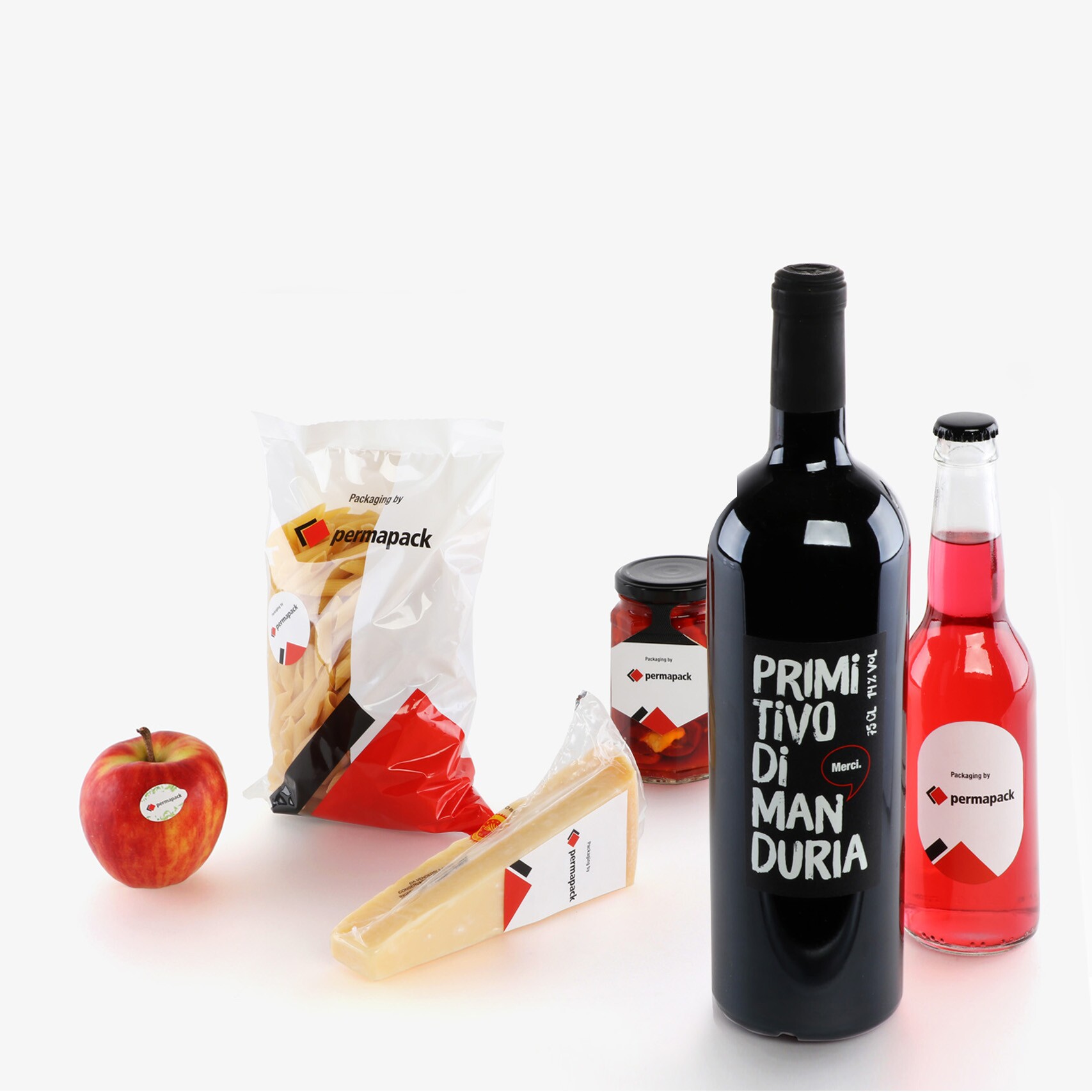 Zwei Flaschen, ein Apfel, ein Beutel, ein Glas und ein eingepacktes Stück Käse bestückt mit bedruckten Etiketten.