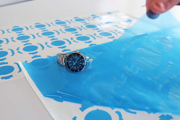 La grille de découpe est retirée d'une feuille de pièces découpées bleues et une horloge est posée sur la feuille.